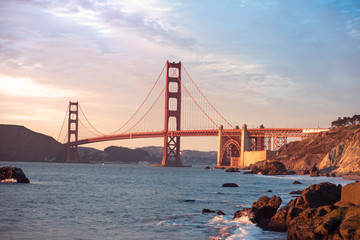 Classic panoramic view of famous Golden Gate Bridge seen from Baker Beach in beautiful golden evening light. San Francisco, California, USA