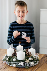 Young boy lighting the first candle on Advent Wreath on the first Sunday in December. Celebrating...