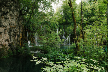 Fototapeta na wymiar Travel to Croatia. Plitvice Lakes is a popular Croatian national park of incredible beauty. Photo of a favorite point among tourists - a stunning waterfall surrounded by greenery