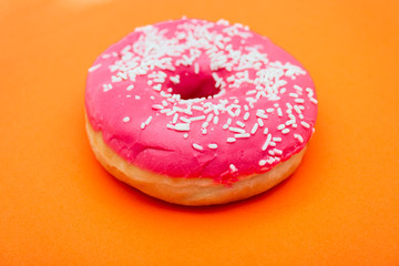 pink donut with sprinkles isolated on orange background