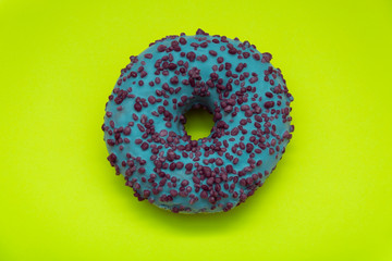 blue donut with colorful sprinkles isolated on green background. Top view.
