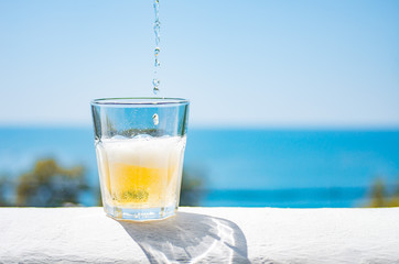 Cold lemonade is poured into a glass. A glass of refreshing lemonade against the backdrop of the sea.