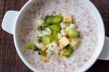 Vegetarian breakfast: milk oatmeal with banana, pear and kiwi slices