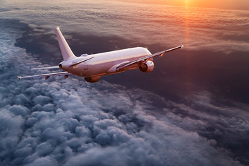 Commercial airplane flying above dramatic clouds.