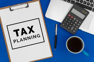 Tax Planning on Paper. Top View of Laptop, Calculator and Coffee Cup on Blue Office Desk. Business...