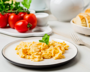 Scrambled eggs, Omelette. Breakfast with pan-fried eggs, cup of tea, tomatoes on white stone marble background. Side view