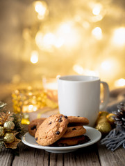 Christmas background with Chocolate chip cookies, cup of tea. Cozy evening, mug of drink, Christmas decorations, candles and lights garlands