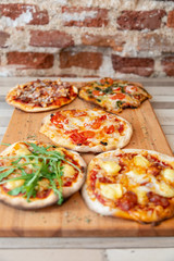 five pizzas on a wooden board on a wooden table