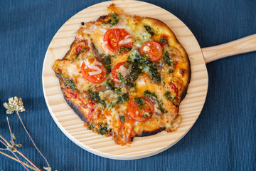 Top view of tomato and pesto pizza on a wooden board