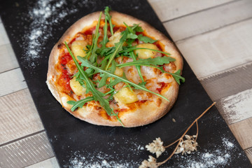 Top view of pizza with arugula on a blackboard garnish with flour