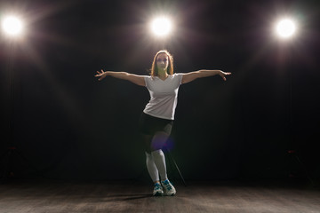 Dance, hip-hop, jazz funk and people concept - flexible young woman dancing in the darkness under the light