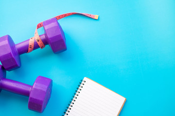 Fitness equipment dumbbells on color background. Flat lay.