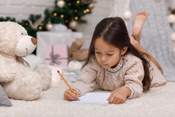 Cute child girl writing letter to Santa Claus at home