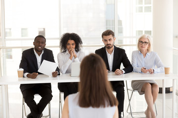 Serious focused diverse hr recruiting people group listening applicant performance at job interview, multi-ethnic recruiters team make decision consider hiring seeker thinking about first impression - obrazy, fototapety, plakaty