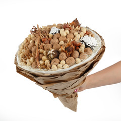 Decorative bouquet consisting of various nuts in the hand of a woman on a white background