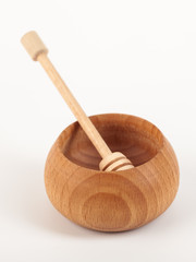 Wooden honey dipper and bowl isolated over white background