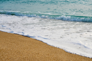 Sunset at the beach, waves with foam hitting sand.