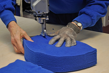 commercial textiles worker cutting a pile of fabric
