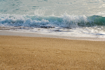 Sunset at the beach, waves with foam hitting sand.