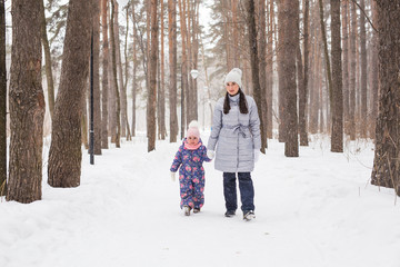 Fototapeta na wymiar Happy family mother and child daughter having fun, playing at winter walk outdoors