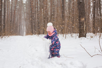 Fototapeta na wymiar Childhood and children concept - baby girl walk in the winter outdoors