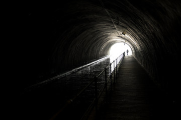 Silhouette Of An Appraching Man In Front Of Bright Light At The End Of A Dark Tunnel