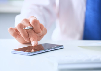 Businessman using smart phone in office close up.