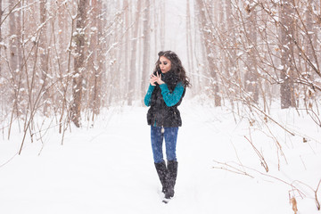 Fototapeta na wymiar Winter, season and people concept - Young pretty woman walking in snowy park