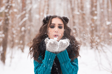 Christmas Girl. Winter young woman blowing snow in winter nature