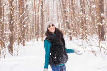 Walks, season and people concept - happy young woman with snow in winter park