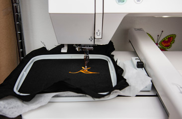 Machine à broder en action sur un tissu noir, gros plan d'une machine à broder industrielle en...