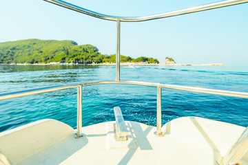 nose of boat with blue sea water and land on background