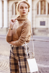 Outdoor fashion portrait of young beautiful fashionable girl wearing trendy beige cashmere...