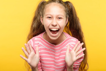 overexcited enthusiastic laughing girl. child portrait on yellow background. emotion and facial...