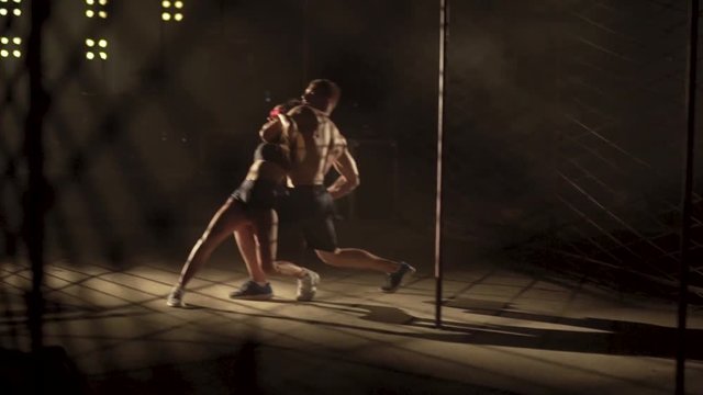 girl and boy are training fighting. martial arts battle without rules in cage battle without rules