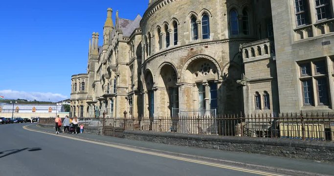 Aberystwyth Wales family walks by old buildings. Ancient market town, administrative center, community, and holiday resort in Ceredigion, Wales. Tourist destination.
