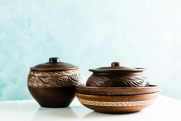 pots and plates of clay on a white table and a blue background. clay pottery kitchen utensils made by hand. red clay tableware