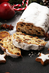 Traditional European Christmas pastry, fragrant home baked stollen, with spices and dried fruit. Sliced on rustic table with xmas tree branches and decorations