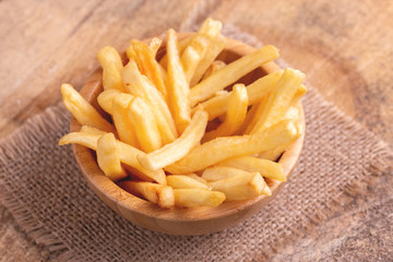 Tasty french fries in wooden bowl on burlap napkin
