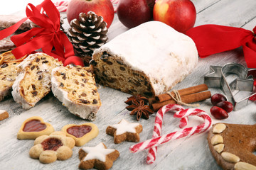Traditional European Christmas pastry, fragrant home baked stollen, with spices and dried fruit. Sliced on rustic table with xmas tree branches and decorations
