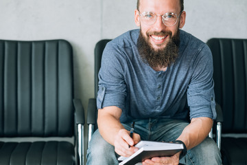 business coach or career mentor. smiling bearded man in glasses with notebook.