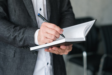 man hand writing in notebook. business planning or agenda concept.