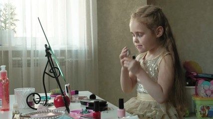 a little girl with red hair sprinkles perfume or toilet water, looks in the mirror, makeup, face, fashion, style, cosmetics