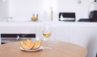 Fototapeta na wymiar A glass of white wine and melon on a kitchen