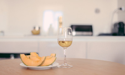 A glass of white wine and melon on a kitchen