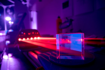 Experiments with lasers in the optics lab. Red laser on optical table in physics laboratory