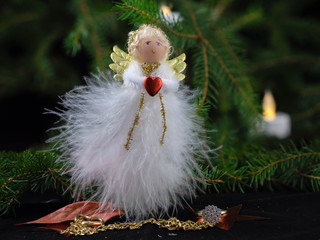 Engel, handgearbeitet aus Federn mit Flügel und Herz vor Weihnachtsbaum