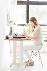 Young business woman working at home and typing on a typewriter. Creative Scandinavian style workspace