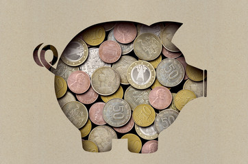Coins under a sheet of paper with a cut out image of a pig
