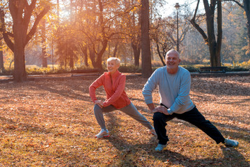 Active senior couple exercising outside in park on beautiful sunny day